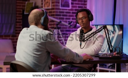 African american famous influencer and guest blogger talking on internet broadcast with sound equipment in home studio. Two men talking in online podcast episode recording for social media channel.