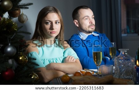 Young man and woman offended after quarrel at table during Christmas dinner Royalty-Free Stock Photo #2205311683
