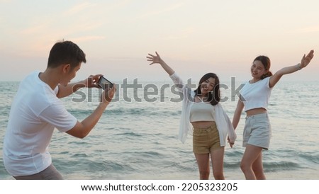 Happy friends smiling and posing taking photo from smartphone and having fun together on beach in holiday vacation time at sunset, Young Asian group woman and man in summer travel outdoor