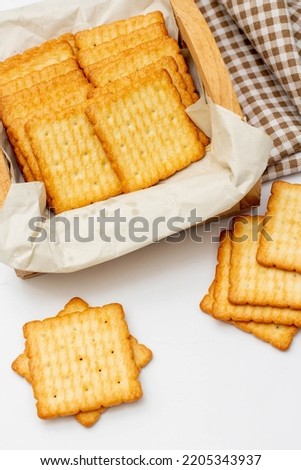 Snack concept, Salty crackers or biscuits are arranged in rows on paper and wooden container.