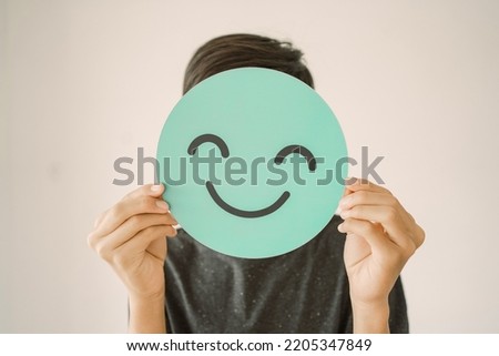 Happy mixed Asian teen boy holding smile emoji face, positive mental health concept Royalty-Free Stock Photo #2205347849