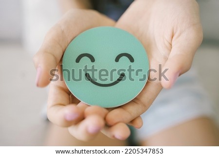 Hands holding green happy smile face paper cut, good feedback rating,think positive, customer review, assessment, child wellness,world mental health day, Compliment Day Royalty-Free Stock Photo #2205347853