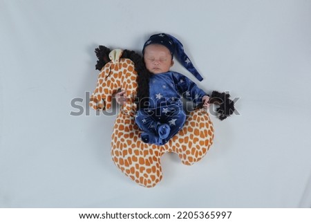 cute baby boy sleeping on a giraffe doll hugging and holding his tail