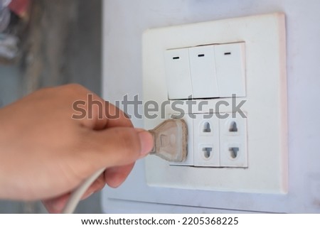 Closeup hand unplug electricity, save power and energy home and routine concept copy space for text and design