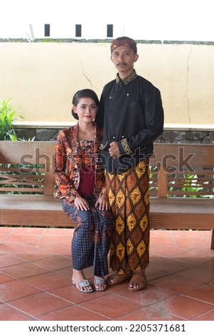 a photo of a man and woman wearing Javanese traditional attire at a photo shoot for prewedding