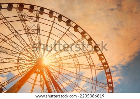 Beautiful large Ferris wheel against blue cloudy sky on sunny day, low angle view