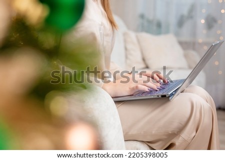 Christmas shopping online, sales and discounts promotions during winter holidays, online shopping at home. Female hands on the laptop with gifts and blurred bokeh lights. High quality photo