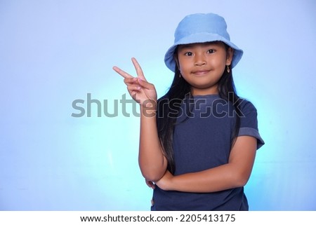 A child with a cheerful expression posing for the camera on a blue background