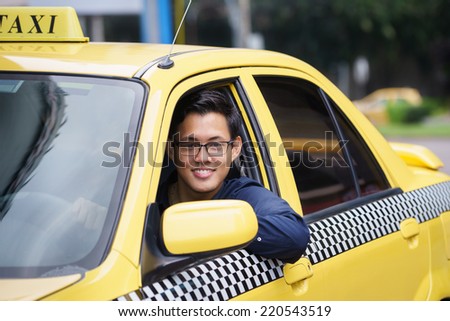 Portrait of happy chinese taxi driver in yellow car smiling and looking at camera Royalty-Free Stock Photo #220543519