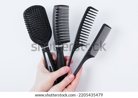 A set of black hair combs in the hands of a caucasian woman. White background.
