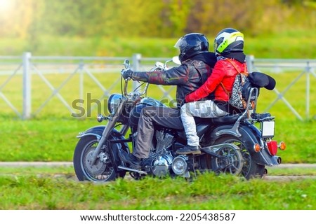 Biker on a motorcycle with a passenger rides on a road in the city on a bright sunny day. The concept of motorcycle travel and adventure. Royalty-Free Stock Photo #2205438587