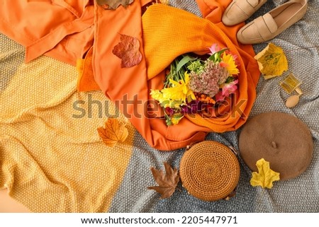 Female clothes, stylish accessories, bouquet of flowers and autumn decor on grey plaid