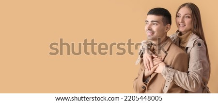 Fashionable young couple in autumn clothes on beige background with space for text