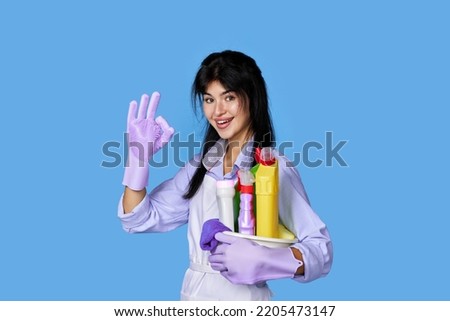 woman in gloves holding bucket of detergents and showing Ok gesture