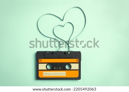 Music cassette and hearts made with tape on turquoise background, top view. Listening love song Royalty-Free Stock Photo #2205492063
