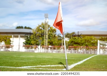 Closeup red flag in a football ground corner with bright blue sky.
