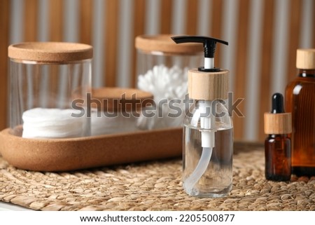 Bottle with dispenser cap and essential personal hygiene products on table indoors