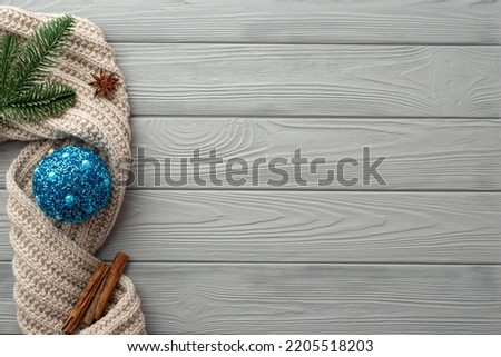 Christmas decorations concept. Top view photo of blue sparkle bauble pine branch knitted scarf anise and cinnamon sticks on grey wooden desk background with copyspace