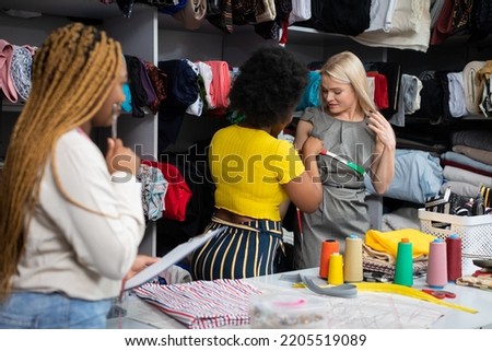 A dark-skinned seamstress measures the client's chest circumference. Royalty-Free Stock Photo #2205519089