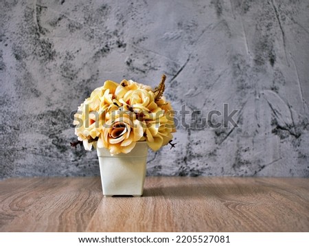 Decoration artificial flowers bouquet in pot on table with old cement wall background, Yellow Rose flowers ,copy space ,Flora home decor ,mother's day ,still life ,women's day festive background