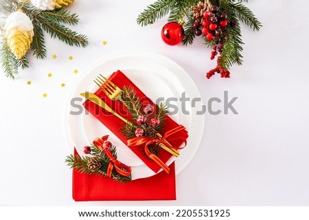 festive serving of the Christmas table in white red tones. gold cutlery decorated with trinkets. top view. white background