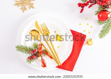beautiful festive setting of the New Year's table. white plates, a gold set of cutlery, balls, snowflakes, a spruce branch. top view