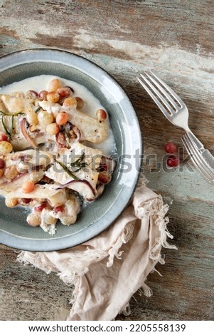 a plate with baked halibut fillet in a creamy sauce with grapes