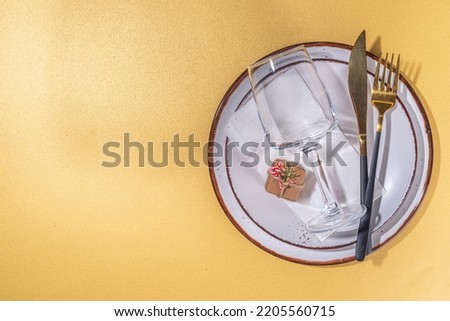 Xmas holiday table place setting, Christmas, Thanksgiving, New Year dinner table setting flat lay with plates, fork and knife, empty champagne wine glass, on golden background top view copy space