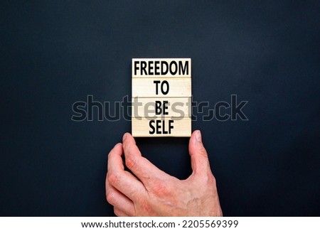 Freedom to be self symbol. Concept words Freedom to be self on wooden blocks on a beautiful black table black background. Businessman hand. Business, psychological freedom to be self concept.