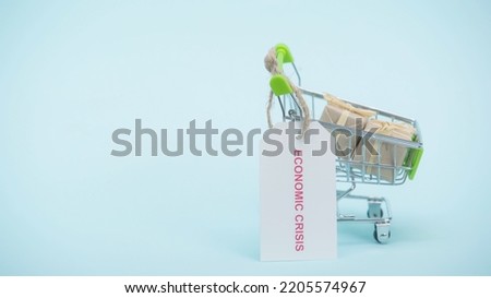 small shopping cart with gifts and card with economic crisis lettering on blue background