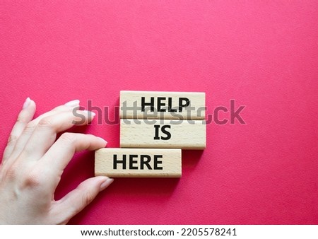 Help is here symbol. Wooden blocks with words Help is here. Beautiful red background. Businessman hand. Business and Help is here concept. Copy space.