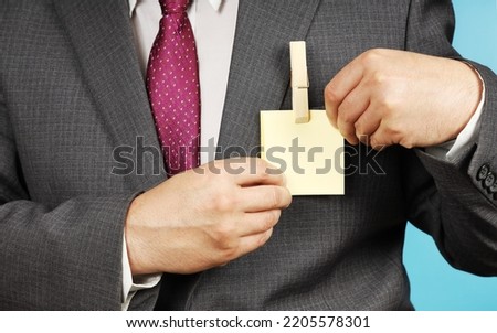 Businessman in suit shows his badge, where sticker and clothespin is attached instead of nametag, copy space for text