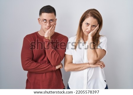Mother and son standing together over isolated background thinking looking tired and bored with depression problems with crossed arms. 