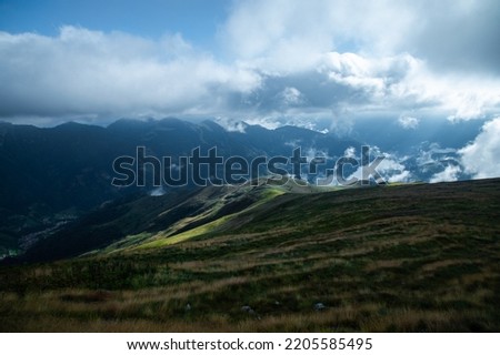 Mountain panorama of alpine valley with natural meadows and dramatic clouds, Collio valley, Brescia territory, northern Italy