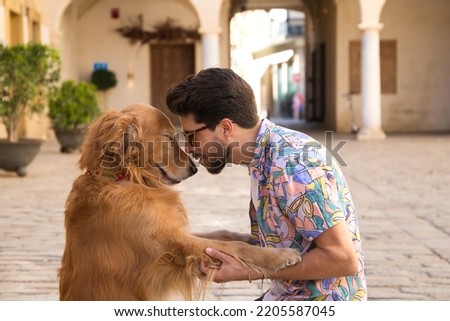 young latino man and his brown golden retriever dog kneeling on the ground while looking at each other with their heads together in sign of affection and love. Concept pets, animals, dogs, pet love. Royalty-Free Stock Photo #2205587045