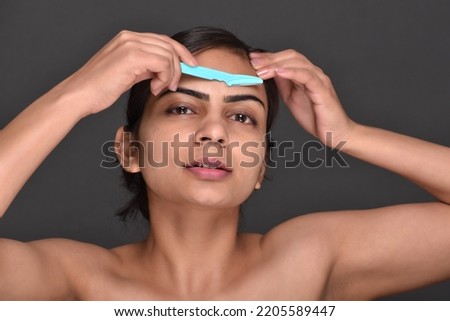 Young woman using eye brow trimmer 