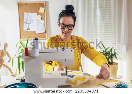 Woman sewing on a sewing machine at her home. Woman seamstress work on the sewing-machine Royalty-Free Stock Photo #2205594871