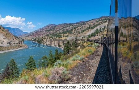 Rocky Mountaineer train riding along the Fraser River in British Colombia, Canada. Focus on train. Royalty-Free Stock Photo #2205597021