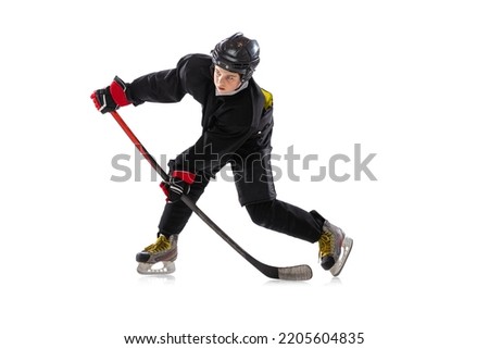 On the run. Child, hockey player with the stick on ice court and white background. Sportsman wearing equipment and helmet practicing. Concept of sport, healthy lifestyle, motion, movement, action.