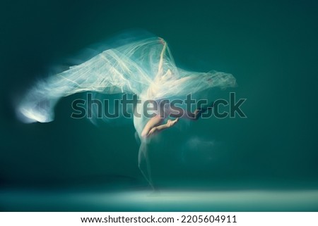 Emotions in dance. Graceful ballet dancer dancing with white cloth, fabric isolated on green background. Concept of art, motion, action, flexibility and inspiration concept. Blurring effect