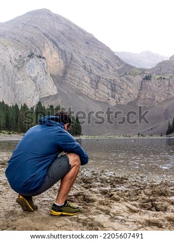 young boy in navy blue jacket taking pictures of a lake in the m