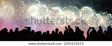 People admire salute in the Moscow on May 9. Making photos. The celebration of win in the Grate Patriotic War. Image in black silhouettes. Fireworks as background. Night city street. Backs, rear view