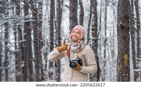 Taking stunning winter photos. Winter hobby. Enjoy enchanting paleness and freezing atmosphere of winter. Enjoy beauty of snow scenery through photos. Woman photographer with professional camera
