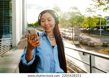 Asian brunette woman taking selfie photo on cellphone at city street