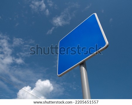 Blank blue street sign template for mock up. Low angle view. Blue sky with clouds in the background