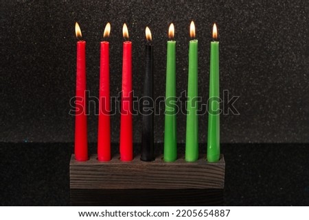 Kwanzaa festival concept with seven candles red, black and green in candlestick on black background, copy space