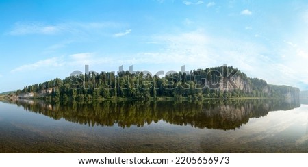 Limestone rocks overgrown with coniferous forest on the bank of a mountain lek river in summer in sunny weather. High resolution photo. Vishera river, Govorlivyy stone, Perm region, Russia
