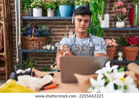 Hispanic young man working at florist shop doing video call with open hand doing stop sign with serious and confident expression, defense gesture 