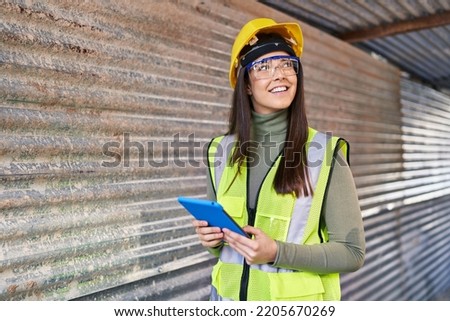 Young beautiful hispanic woman architect smiling confident using touchpad at street