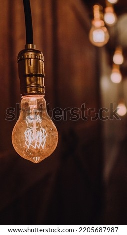 The picture shows a light bulb shinning dimly. Comes with a background of few more dim lights .Showing light and dark at the same time